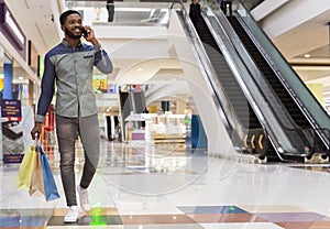 Handsome african man with shopping bags talking by cellphone photo