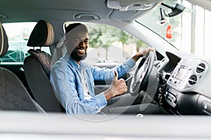 Handsome african man show thumbs up inside car