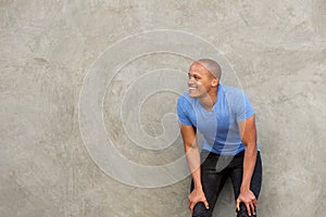 Handsome african man smiling with hands on knees