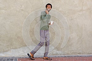 Handsome african man walking with smart phone and coffee cup