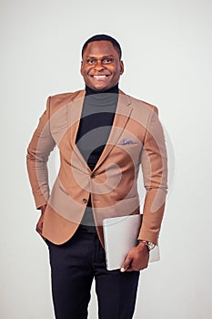 Handsome Afro American man in classic suit smiling and using a laptop in the studio on a white background