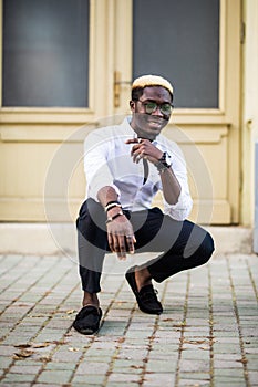 Handsome Afro American man wearing casual clothes in modern city sitting near the building