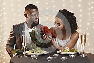 Handsome afro man giving beautiful flowers to his woman