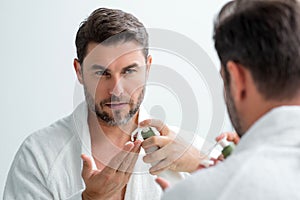 Handsome aged man applying face cream. Beauty routine. Man with perfect skin. Anti-aging and wrinkle cream. Concept of