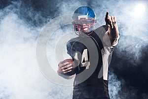 handsome american football player with ball pointing somewhere against