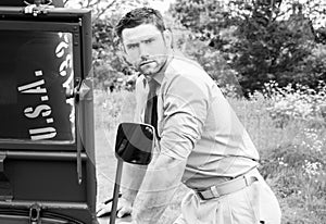 Handsome American WWII GI Army officer in uniform and rolled up sleeves next to broken down Willy Jeep