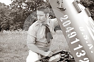 Handsome American WWII GI Army officer in uniform and rolled up sleeves next to broken down Willy Jeep