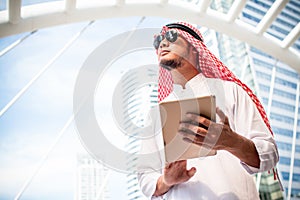 Handsome arab business man hold the digital tablet and looking to left side. Arab business man standing outside office.