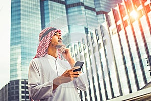 Handsome arab business man hold smartphone and looking to right side. Arab business man standing outside office