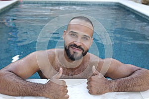 Handsome Arabic man giving thumbs up in swimming pool