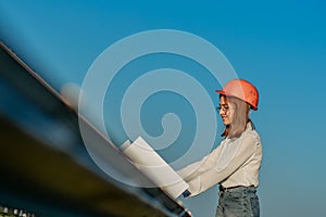 Handsome Architect Woman Examining a Draft Map or Blueprint Project Plan, Worker Activity Looking Out in Photovoltaic Cell Farm or