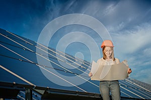 Handsome Architect Woman Examining a Draft Map or Blueprint Project Plan, Worker Activity Looking Out in Photovoltaic Cell Farm or