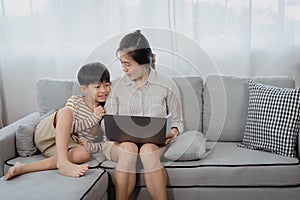 Handsome Asian boy ran up to his mother and sat down next to him, while his mother was working on a laptop computer, His mother