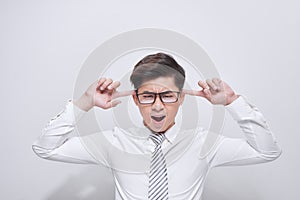 Handsome asian businessman covering his ears over white background