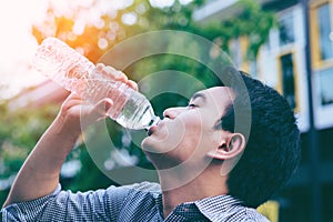 Handsome asian businessman drinking water ifrom a bottle