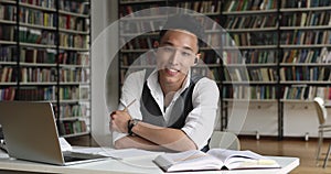 Handsome Asian college student sit in library studying use laptop
