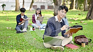 Handsome Asian male college student doing homework in the campus`s park in the afternoon