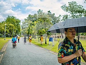 Handsome Asian male wear hawai t -shirt Holding umbrella and walking in the Chatuchak park