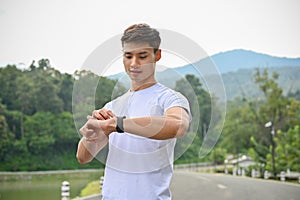 Handsome Asian man checking his calories burned from running on his smart watch