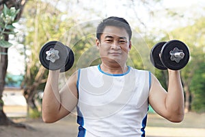 Handsome Asian man exercises outdoor, lift dumbbell.