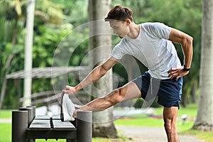 Handsome asian man in sportswear stretching legs, warming up before morning workout at outdoors. Healthy lifestyle