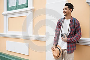 Handsome Asian man tourist Standing at wall While holding a straw hat at Attractions in Bangkok, Thailand, Solo travel and