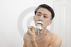 Handsome asian man trying shave beard