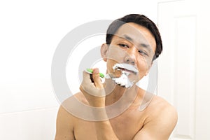 Handsome asian man trying shave beard