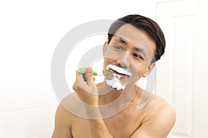 Handsome asian man trying shave beard