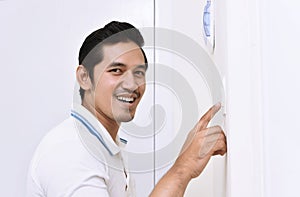 Handsome asian man turning off the light with wall switch