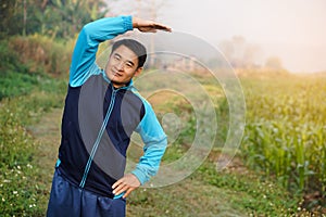 Handsome Asian man workouts outdoor, body stretching. Warm up before or cool down after exercise.