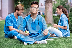 handsome asian medical student holding apple and looking