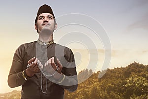 Handsome asian muslim man holding prayer beads and praying