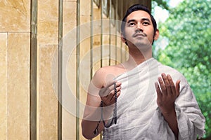 Handsome asian muslim man with ihram holding prayer beads