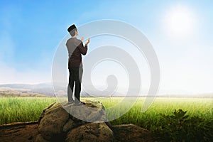 Handsome asian muslim man praying with standing on stone