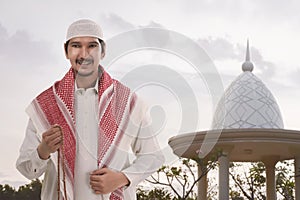 Handsome asian muslim man with white cap holding prayer beads