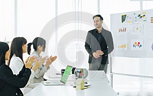 Handsome Asian smart formal businessman presenting and pointing at marketing financial graph or chart on whiteboard to his