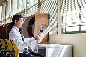a handsome Asian student reading newspaper
