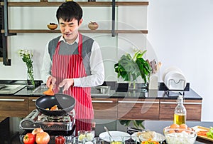 Handsome, Asian young man Smiling happiness.  Frying sausages in a pan for  food