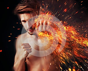 Handsome athlete punching with flame around his fist photo
