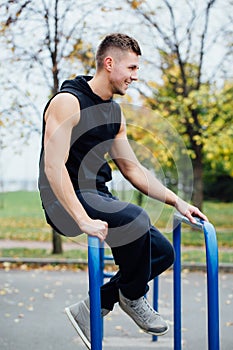 Handsome athlete resting on the bars between sets .