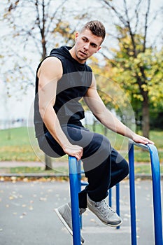 Handsome athlete resting on the bars between sets .