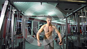 Handsome athletic guy doing pectorals on the crossover trainer in the gym. front view.