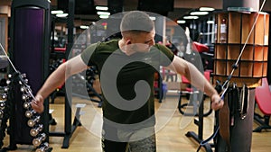 Handsome athletic man doing pectorals on the crossover trainer in the gym. Shot in 4k