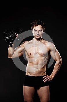 Handsome athletic man with dumbbells confidently looking forward