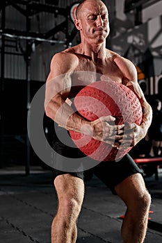 Handsome athletic man is exercising with medicine ball cross fit training, at gym