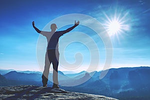 Handsome athletic man, a tourist, stay on summit rock. Wild misty mountain landscape