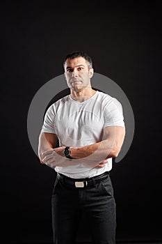 Handsome Athletic man in white blank t-shirt standing on black wall background