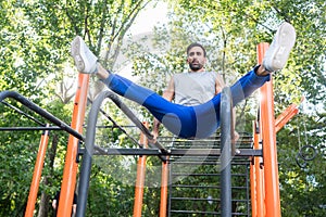 Handsome athletic young man exercising vertical leg raise in an