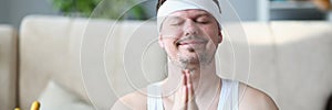 Handsome athletic young man presses hands to chest in namaste nirvana pose